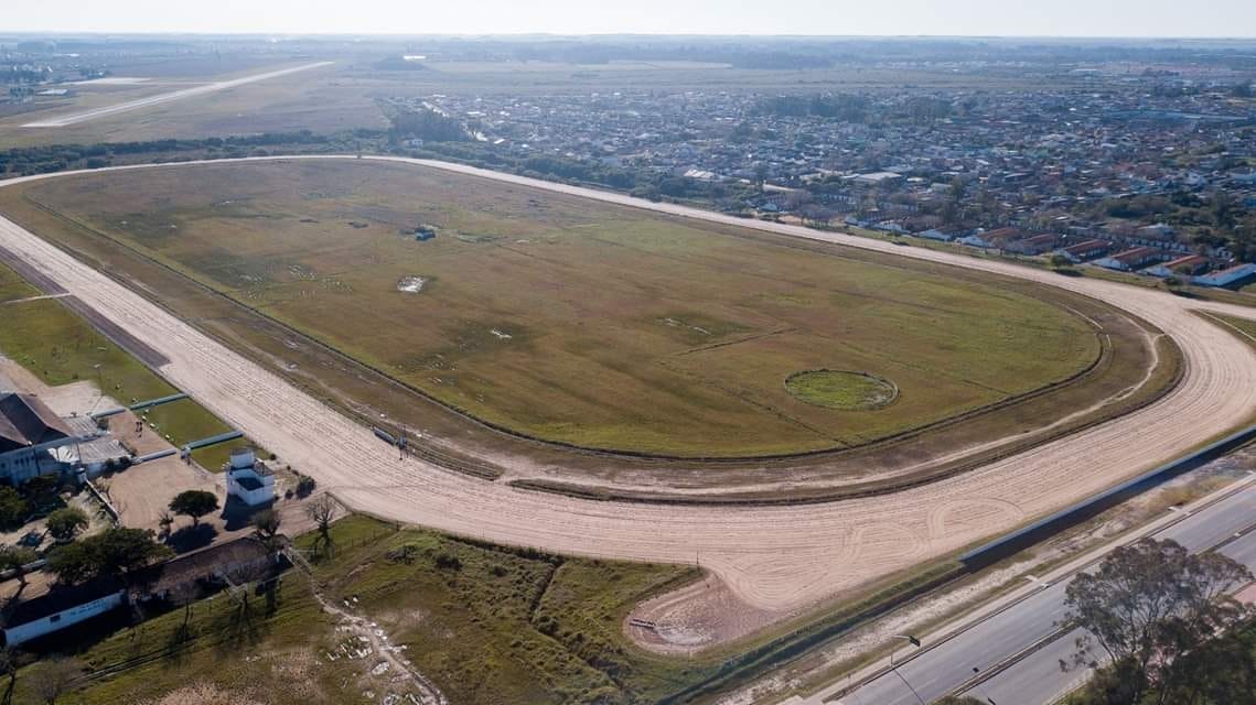 Vista aérea do Hipódromo da Tablada: a pista oval de areia, a arquibancada e a cidade de Pelotas ao fundo